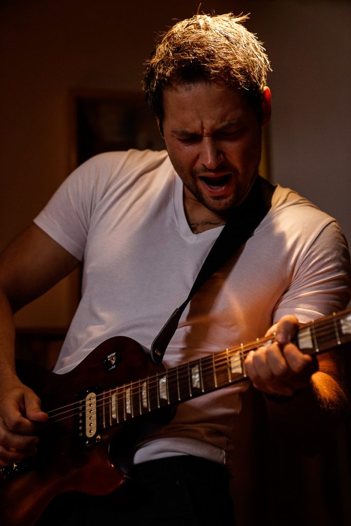 Gitarrist spielt und singt im warmen Bühnenlicht