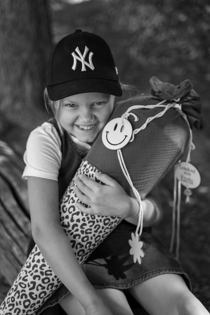 Mädchen mit Basecap hält eine Schultüte, Schwarzweißaufnahme